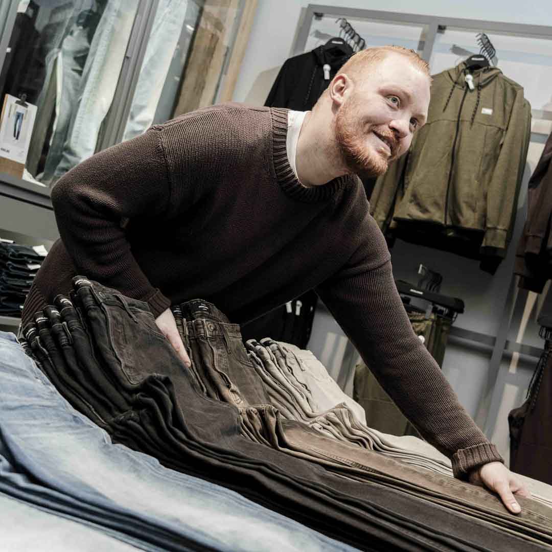 Medarbejder fra Jack & Jones på Nørrebro, lægger jeans pænt på plads.